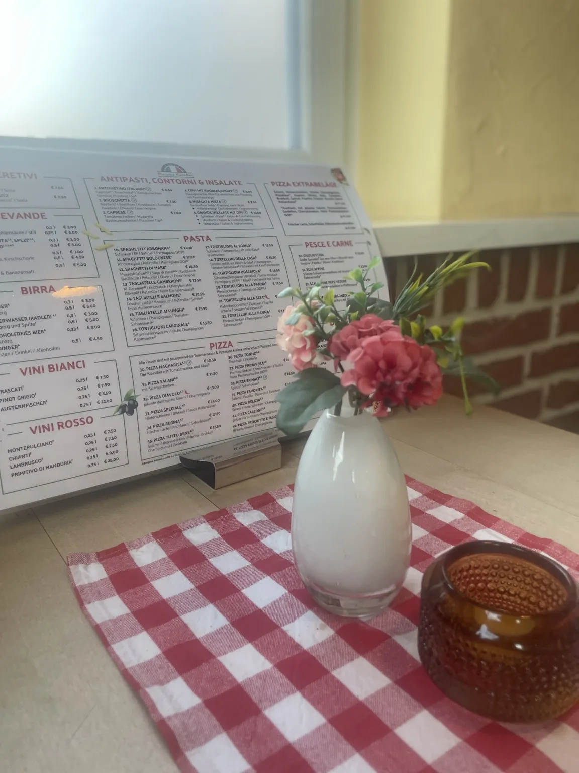 Tisch mit roten Blumen und Speisekarte